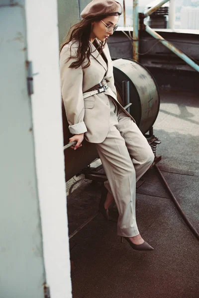 Attractive stylish girl posing in beige suit and beret on urban roof — Stock Photo