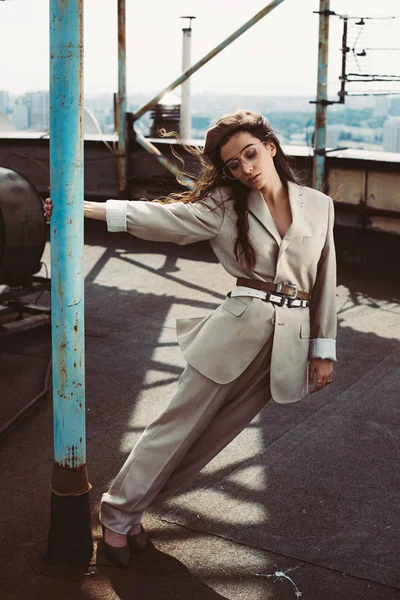 Menina elegante atraente posando em terno bege e boina no telhado urbano — Fotografia de Stock