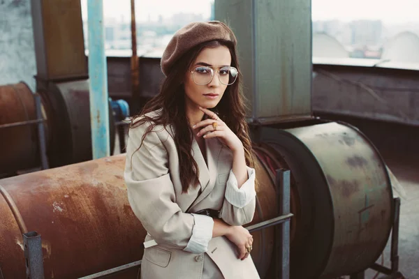 Elegant stylish model posing in beige suit and beret on urban roof — Stock Photo