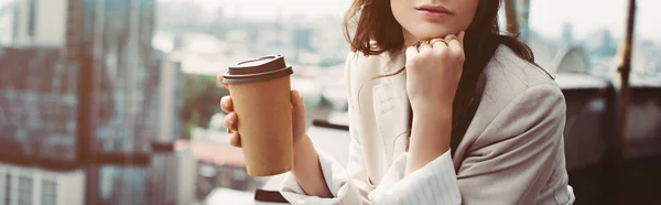 Cropped view of thoughtful fashionable girl in beige suit posing on roof with coffee to go — Stock Photo
