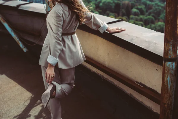 Vista ritagliata di elegante donna alla moda in posa in abito beige sul tetto urbano — Foto stock