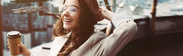 Sorridente ragazza alla moda in abito beige e basco in posa sul tetto con caffè per andare — Foto stock