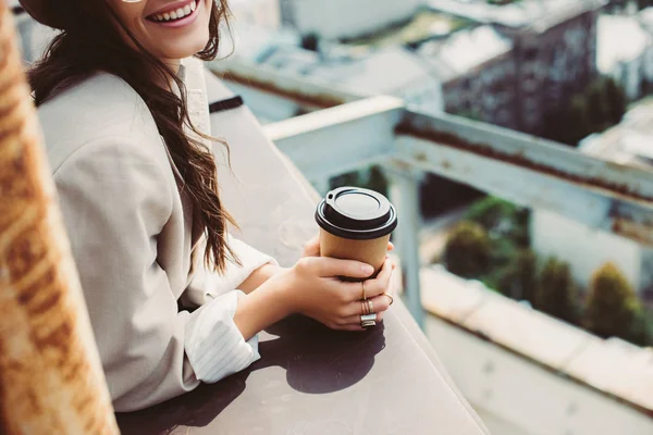 Vista cortada de menina elegante sorridente em terno bege posando no telhado com café para ir — Fotografia de Stock