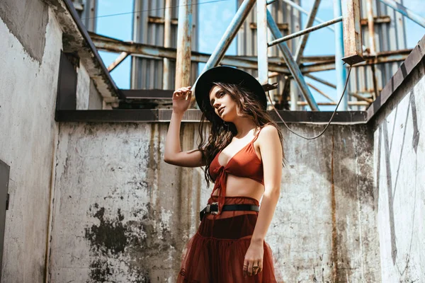 Beautiful woman posing in red skirt, bra and hat on roof — Stock Photo