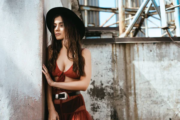 Atractiva mujer de moda posando en falda roja, sujetador y sombrero en el techo - foto de stock