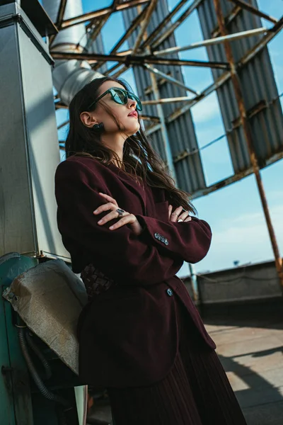 Elegant young woman posing in trendy burgundy suit and sunglasses on urban roof — Stock Photo