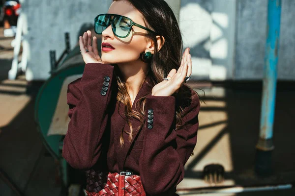 Fashionable girl posing in trendy burgundy suit and sunglasses on urban roof — Stock Photo