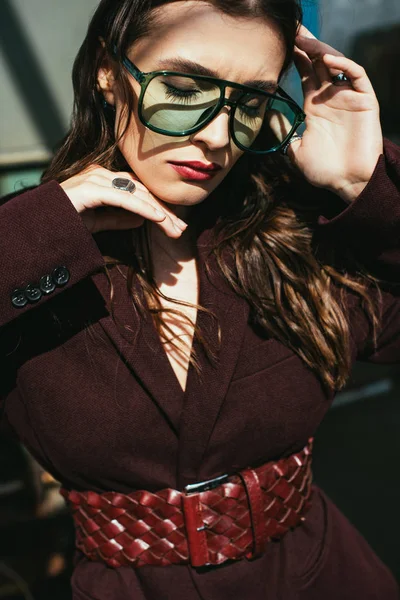 Elegant girl posing in trendy burgundy suit and sunglasses on urban roof — Stock Photo