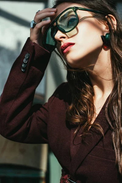 Fashionable woman posing in trendy burgundy suit and sunglasses on urban roof — Stock Photo