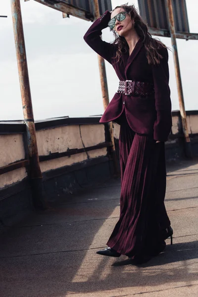 Mulher elegante posando em terno borgonha na moda e óculos de sol no telhado urbano — Fotografia de Stock