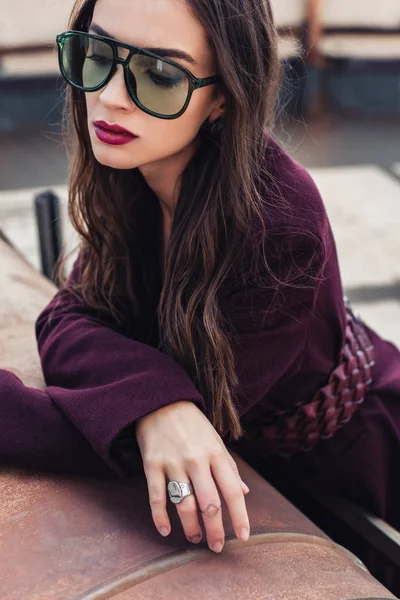 Atractiva chica elegante posando en traje de moda de color burdeos y gafas de sol en el techo urbano - foto de stock