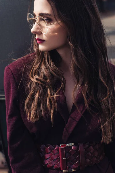 Fashionable girl posing in trendy burgundy suit and sunglasses on urban roof — Stock Photo