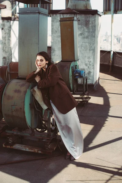 Elegante menina elegante posando em vestido de seda e casaco marrom no telhado — Fotografia de Stock