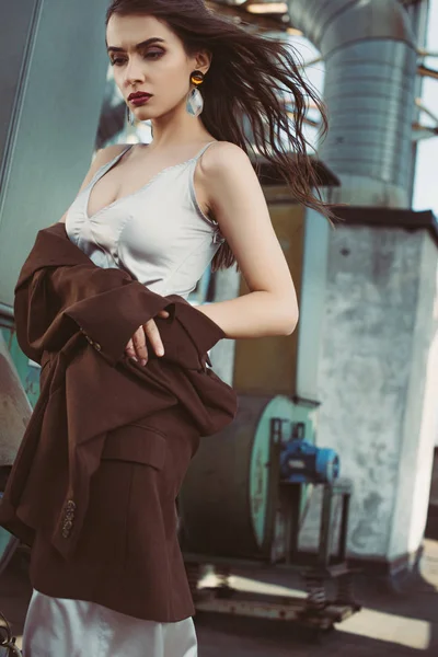 Beautiful elegant girl posing in silk dress and brown jacket on roof — Stock Photo