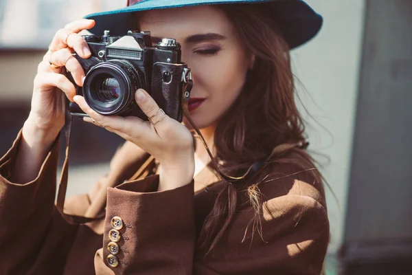 Mujer atractiva en sombrero tomar fotos en la cámara de fotos retro en el techo - foto de stock