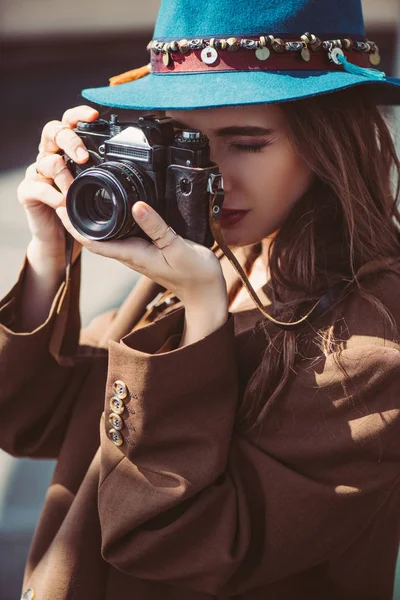 Beautiful woman in hat taking photos on vintage photo camera on roof — Stock Photo