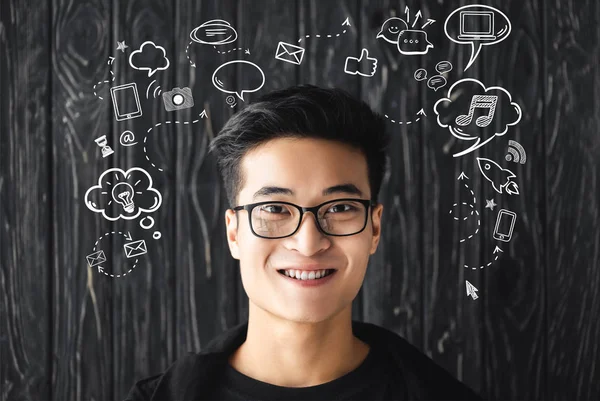 Smiling asian man in glasses looking at camera on wooden background with illustration — Stock Photo
