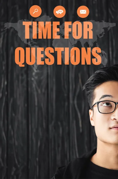 Cropped view of asian man in glasses looking at illustration with time for questions lettering — Stock Photo