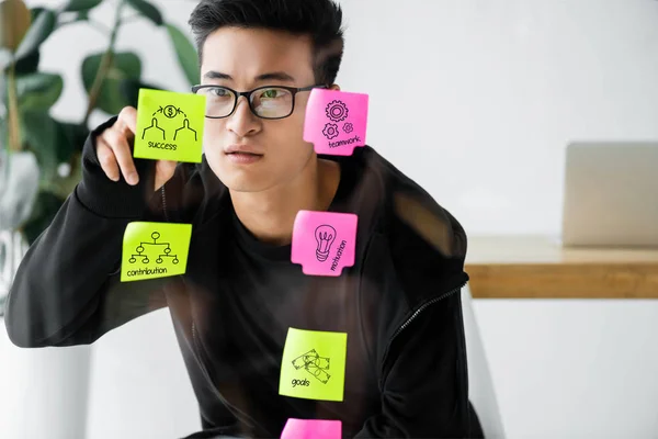Asian seo manager writing on sticky note with illustration — Stock Photo
