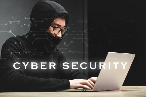 Asian hacker using laptop and sitting near cyber security illustration — Stock Photo