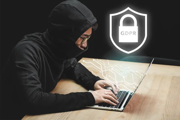 Asiatico hacker utilizzando laptop e seduta vicino lucchetto illustrazione e gdpr lettering — Foto stock