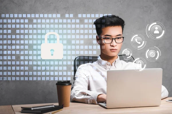 Asian businessman using laptop and sitting near padlock illustration — Stock Photo