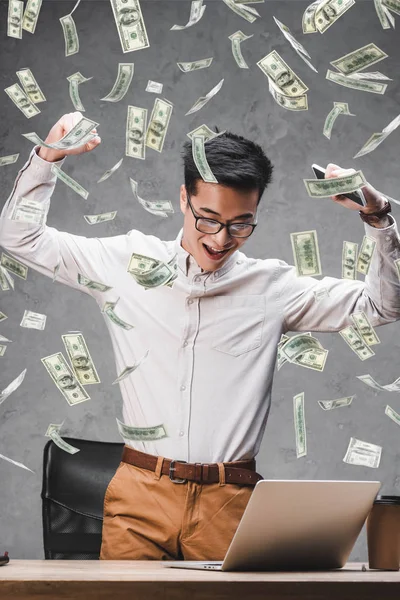 Happy asian businessman showing yes gesture and illustration of dollar banknotes — Stock Photo