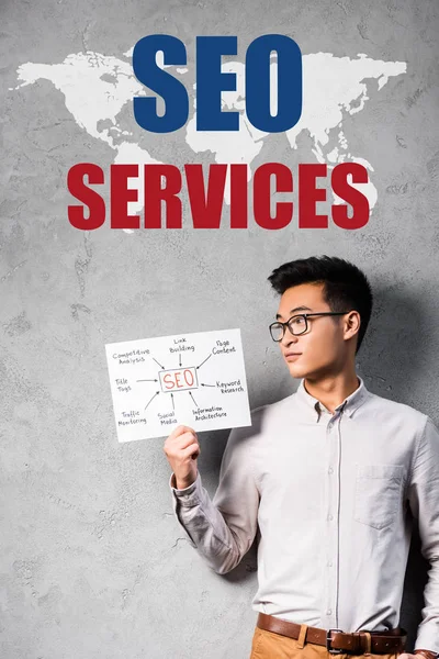 Ásia seo manager segurando papel com conceito palavras de seo e pé perto seo serviços ilustração — Fotografia de Stock