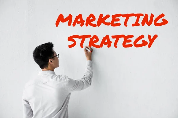 Rückseite des SEO-Managers, der an die Wand schreibt, mit Illustration der Marketingstrategie — Stockfoto
