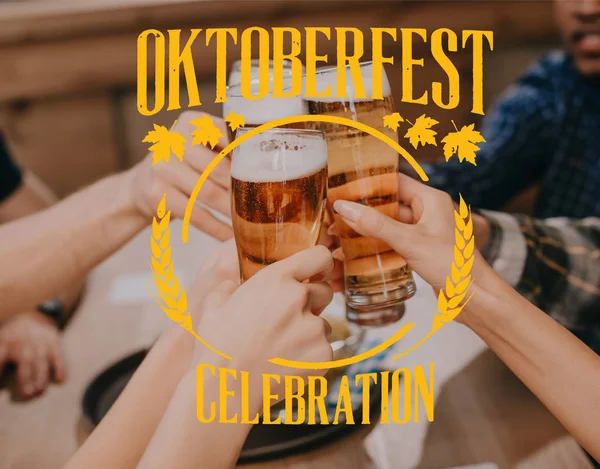 Cropped view of multicultural friends clinking glasses with beer in pub with Oktoberfest celebration illustration — Stock Photo