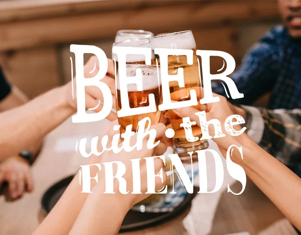 Cropped view of multicultural friends clinking glasses with beer in pub with beer with the friends illustration — Stock Photo