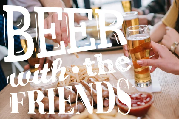 Vista ritagliata di amici che bevono birra e mangiano snack nel pub — Foto stock