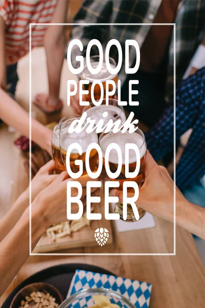 Cropped view of multicultural friends clinking glasses of light beer in pub with good people drink good beer illustration — Stock Photo