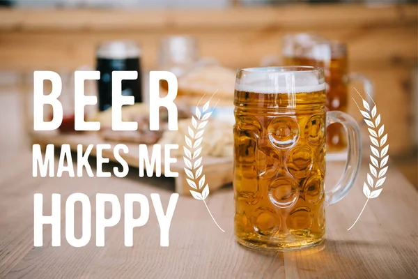 Selective focus of mug with lager beer on wooden table near beer makes me hoppy illustration — Stock Photo