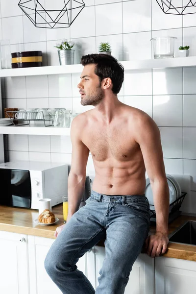 Bel homme torse nu assis sur la cuisine avec petit déjeuner — Photo de stock