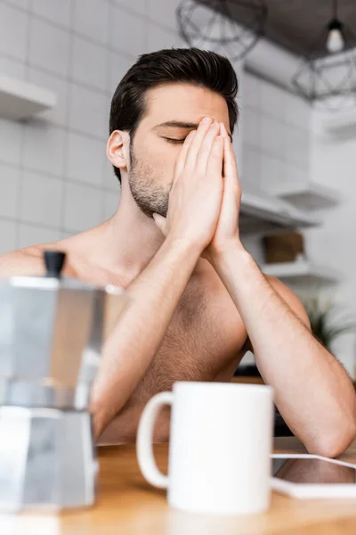 Homme triste torse nu assis sur la cuisine avec cafetière et tasse — Photo de stock