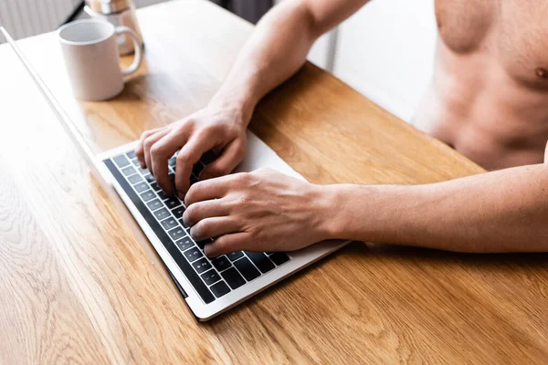 Cropped view of shirtless freelancer working on laptop on kitchen with coffee — Stock Photo