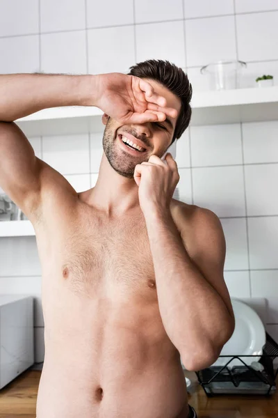 Сексуальный смеющийся мужчина разговаривает по мобильному телефону на кухне дома — стоковое фото