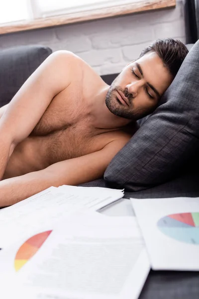 Shirtless freelancer sleeping near documents with charts on sofa during self isolation — Stock Photo