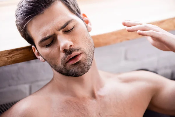 Homem sexy com olhos fechados sofrendo de calor em casa — Fotografia de Stock