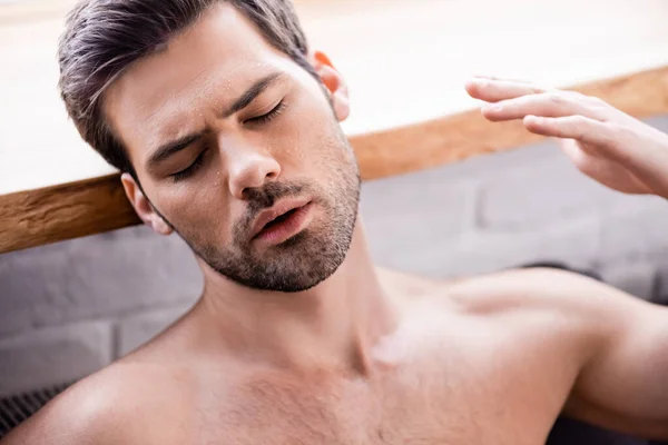 Sexy hombre con los ojos cerrados que sufren de calor en casa - foto de stock