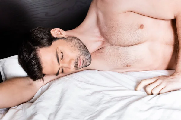 Красавец без рубашки, спящий на кровати дома — стоковое фото