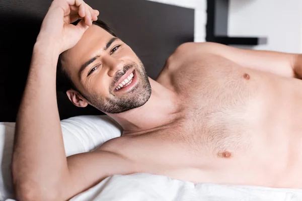 Felice uomo sexy senza maglietta sdraiato sul letto a casa — Foto stock