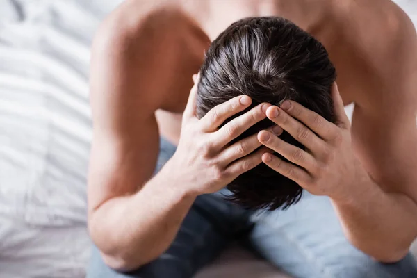 Overhead view of sexy worried shirtless man sitting on bed — Stock Photo