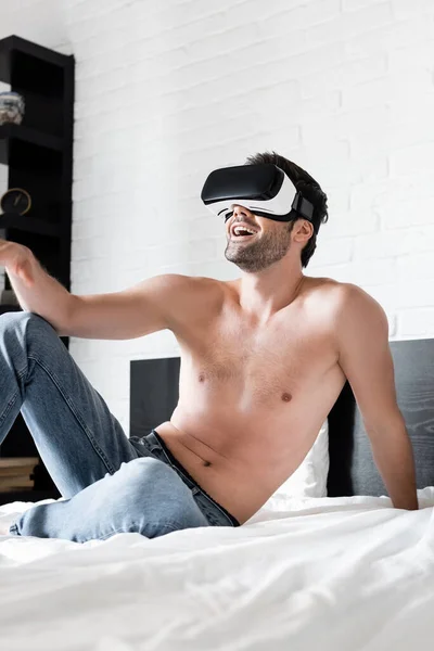 Sexy excité homme geste tout en utilisant la réalité virtuelle casque sur le lit — Photo de stock