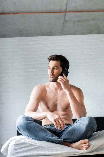 Positive shirtless man using smartphone on bed at home — Stock Photo