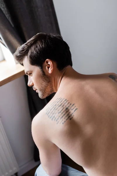 Задний вид сексуального без рубашки татуированный мужчина дома — стоковое фото