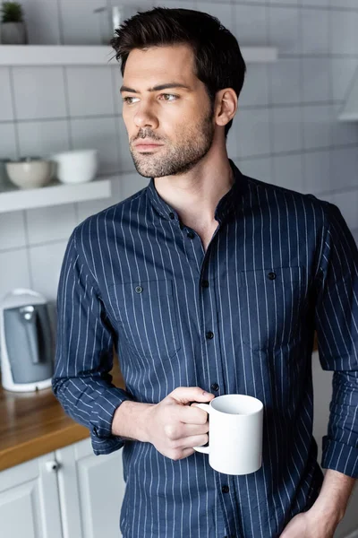 Schöner, nachdenklicher Mann, der zu Hause eine Tasse Kaffee in Quarantäne hält — Stockfoto