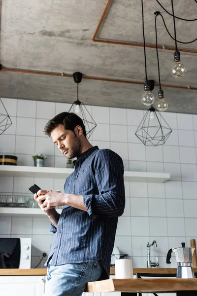 Young man using smartphone on kitchen with coffee during quarantine — Stock Photo