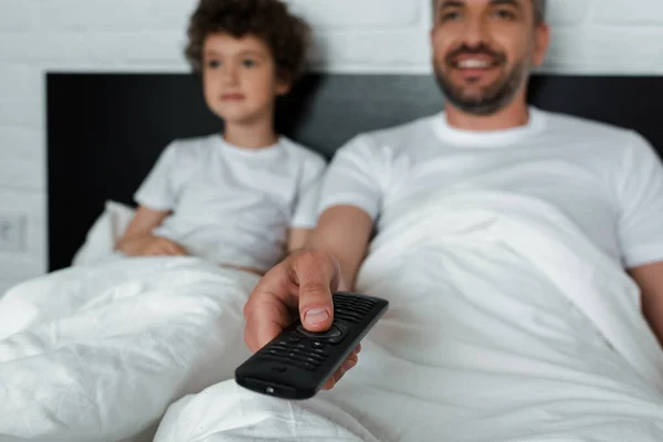 Selective focus of cheerful man holding remote controller near son — Stock Photo